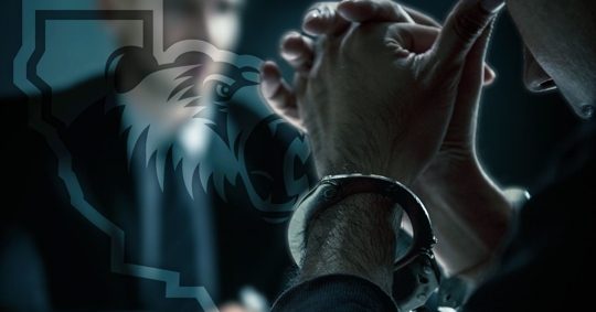 Man with head in hands in handcuffs